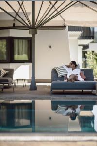 a woman sitting on a couch next to a pool at Hotel loj - our kind of place in Flachau