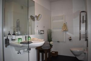 a white bathroom with a sink and a toilet at Hotel Kleißl in Oberperfuss