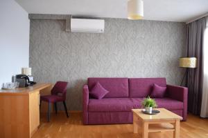 a living room with a purple couch and a table at Hotel Kleißl in Oberperfuss