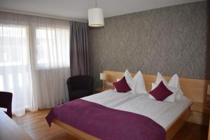 a bedroom with a large bed with a purple blanket at Hotel Kleißl in Oberperfuss