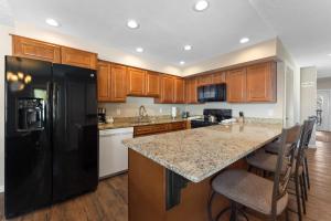 a kitchen with a black refrigerator and wooden cabinets at Rockridge #41 in Breckenridge