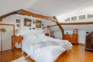 a bedroom with a large white bed and a wooden floor at Cheesemans Cottage in Grimstone