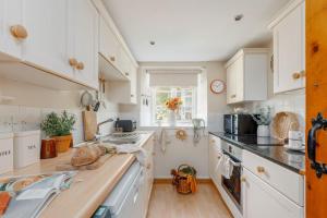 a kitchen with white cabinets and a counter top at Cheesemans Cottage in Grimstone +12 photos