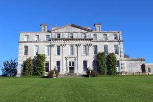 a large white mansion with a large grass field at Cheesemans Cottage in Grimstone