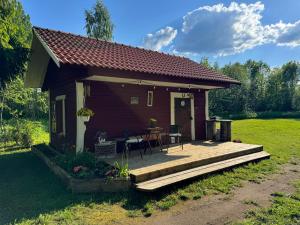 a small house with a wooden deck in a field at Salatse metsa mesionn in Salatse