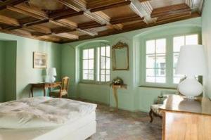 a bedroom with green walls and a bed and windows at Gasthof Hirschen in Eglisau