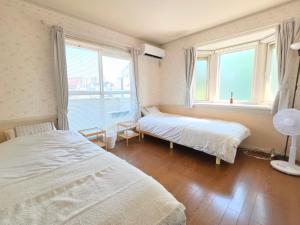 a bedroom with two beds and two windows at 禮 -Rei House- in Muromimachi