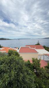 a building with red roofs next to a body of water at Vicko villa in Seget Vranjica