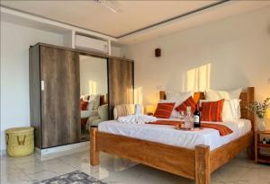 a bedroom with a large bed with orange and white pillows at Casa Samara in Diani Beach +14 photos