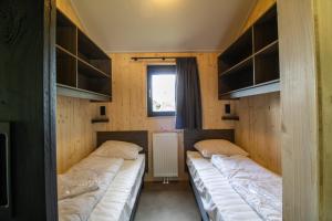 two beds in a small room with a window at Nieuw!! Chalet De Luxe 4 persoons met airco in Oorsbeek +17 photos
