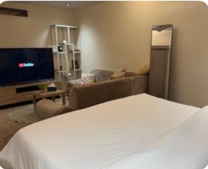 a room with a bed and a couch and a television at نزل بسمة الأبداع in Abha