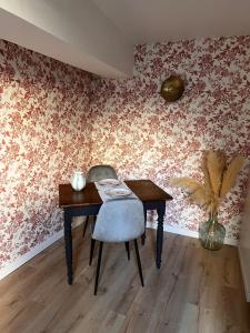 a table and a chair in a room with wallpaper at Cozy independent apartment in Mornant