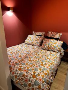 a bedroom with a bed with a floral comforter and pillows at Cozy independent apartment in Mornant