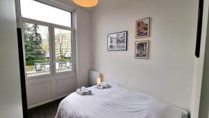 a white bedroom with a bed and a window at AGENCE MOMENT'APART Legend in Mouvaux