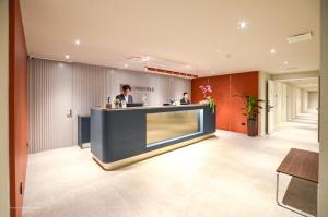 a lobby with a counter with two people in it at CP Hotels - Central in Milan