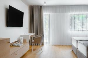 a bedroom with a bed and a desk and a chair at Hotel Băile Bughea in Bughea de Sus