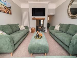 a living room with two green couches and a tv at Ruby's Retreat in Filey