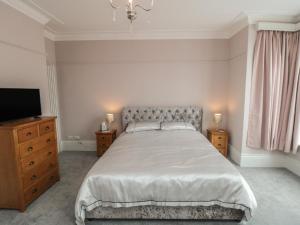 a bedroom with a large bed and a television at Ruby's Retreat in Filey