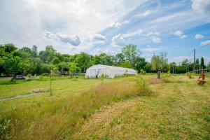 a large field with a greenhouse in the background at Le Gîte du Moulin in Saint-Maigrin