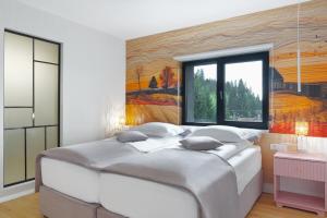 a bedroom with a large bed with a painting on the wall at Hotel Băile Bughea in Bughea de Sus