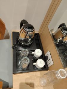 a tea kettle and cups on a stove at Hotel Sun City in Kalol