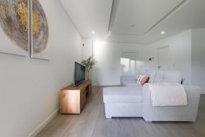 a living room with a white couch and a tv at Villa Piscina Privada 3 Quartos 8 Hóspedes in Fernao Ferro