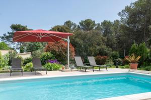 a swimming pool with two chairs and an umbrella at Villa la Rabassa in Lauris