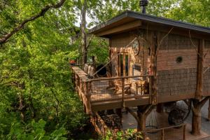 a tree house with a deck in the trees at "Air Fort One" Aviation-Themed Luxury Treehouse Near Dollywood & Pigeon Forge in Sevierville