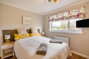 a bedroom with a white bed with yellow pillows and a window at 2 Bed in Ochiltree oc-w37516 in Ochiltree