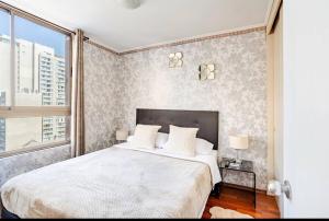 a bedroom with a large white bed and a window at Lupe&Lulu aparments in Santiago