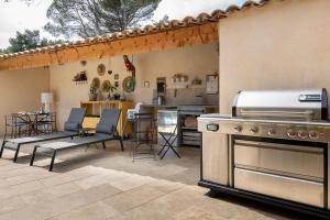a patio with a stove and chairs and a kitchen at Villa la Rabassa in Lauris