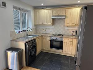 a kitchen with wooden cabinets and a dishwasher at Private Hydro Spa Pool, Dbl Bedrm & Bathrm - Other areas part private shared lived-in home in Bickershaw