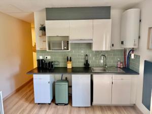 a kitchen with white cabinets and a sink at Numéro 6 in Toulouse +1 photo