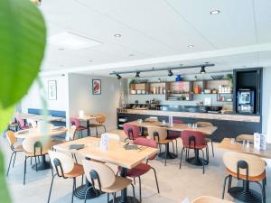 a restaurant with tables and chairs and a kitchen at Ibis Orleans La Chapelle Saint Mesmin in La Chapelle-Saint-Mesmin
