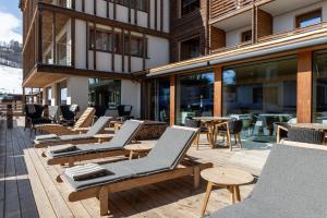 a row of lounge chairs and tables on a patio at Hotel Spol - Adults only in Livigno