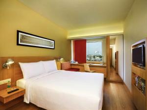 a hotel room with a white bed and a television at ibis Bengaluru Hosur Road - An Accor Brand in Bangalore