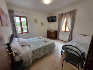 a bedroom with two beds and a television and a chair at B&B Il Tralcio in Cascia