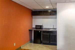 a kitchen with an orange wall and a counter top at Hotel Elizabeth Near Newark Liberty International Airport New Jersey in Elizabeth