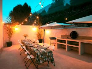 a long table with white chairs and umbrellas on a patio at Casa La Huertona de Castroserna in Castroserna de Arriba