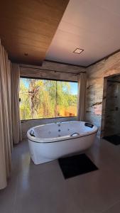 a bath tub in a room with a large window at Pousada Raio de Luz in Pirenópolis +58 photos