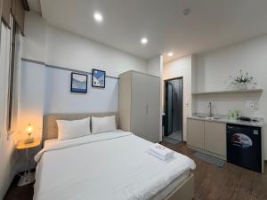 a bedroom with a large white bed and a kitchen at SP house in Ho Chi Minh City