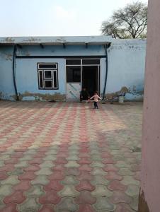a young child standing in front of a building at Joon Farm in Kot Qāsim