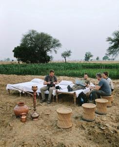 a group of people sitting around a table in a field at Joon Farm in Kot Qāsim