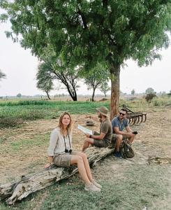 a group of people sitting on logs under a tree at Joon Farm in Kot Qāsim