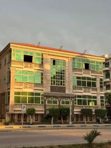 a large building with green windows on a street at Ras elbar Palace in Ras El Bar