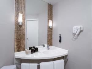 a white bathroom with a sink and a mirror at Ibis Bangkok Riverside in Bangkok +44 photos