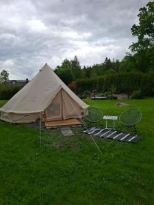 a tent in a field of grass with a bench at Glamping in Alingsås