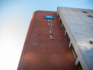 a tall brick building with a blue sign on it at ibis budget Belfast City Centre in Belfast
