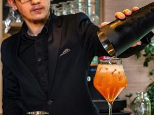 a bartender making a drink in a cocktail glass at Novotel Suites Reims Centre in Reims