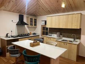 a kitchen with wooden cabinets and a white counter top at Kut House in Pālampur